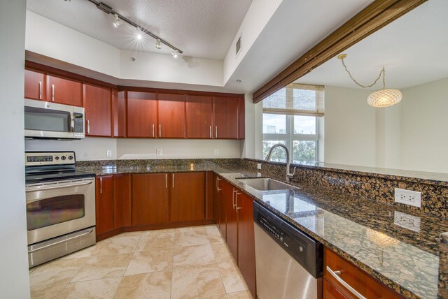 kitchen with sink, dark stone counters, a textured ceiling, light tile patterned floors, and appliances with stainless steel finishes