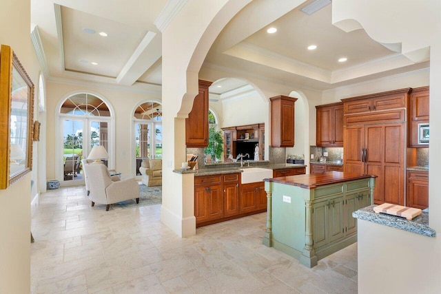 kitchen featuring sink, backsplash, built in appliances, a kitchen island, and ornamental molding