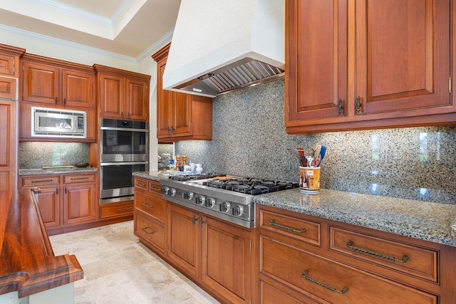 kitchen featuring light stone countertops, custom range hood, appliances with stainless steel finishes, and tasteful backsplash