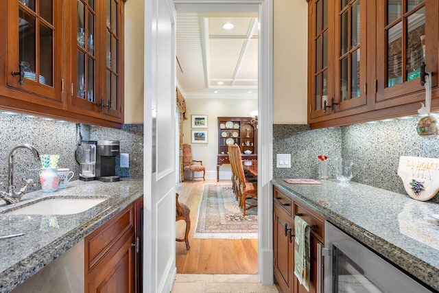 kitchen featuring decorative backsplash, light wood-type flooring, ornamental molding, and sink