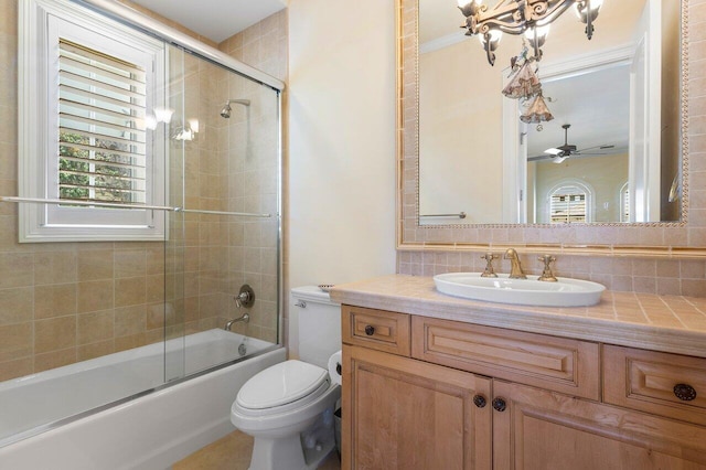 full bathroom with vanity, shower / bath combination with glass door, backsplash, ceiling fan, and toilet