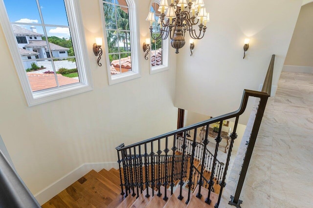 staircase with wood-type flooring and an inviting chandelier