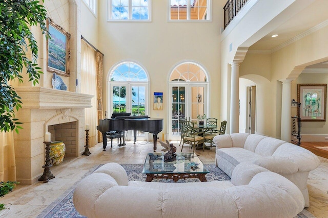 living room featuring ornate columns, crown molding, a premium fireplace, and a high ceiling