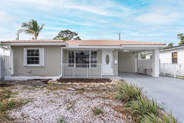 1609 N J Ter, Lake Worth, FL 33460 - ranch-style home featuring stucco siding, driveway, an attached carport, covered porch, and a tiled roof
