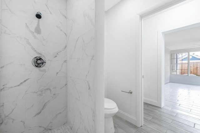 bathroom with a tile shower and toilet