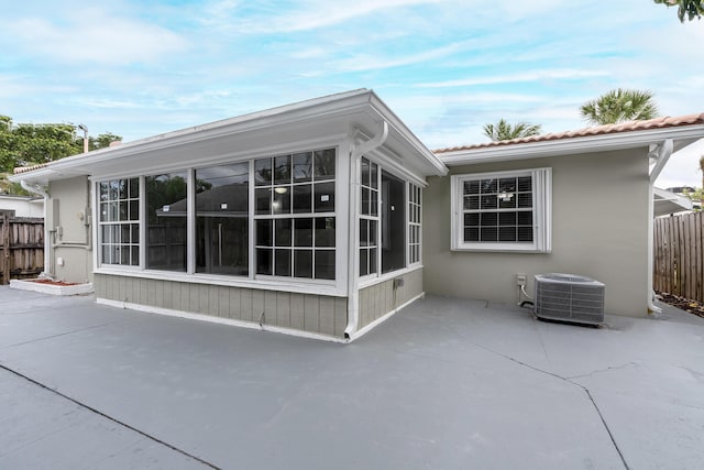 rear view of property featuring a sunroom, a patio area, and central AC