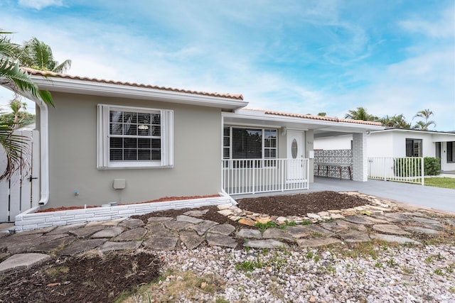 1609 N J Ter, Lake Worth, FL 33460 - view of front facade featuring stucco siding, a tile roof, a carport, and driveway