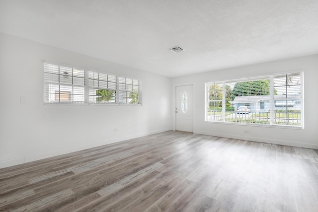 unfurnished room with hardwood / wood-style flooring and a textured ceiling