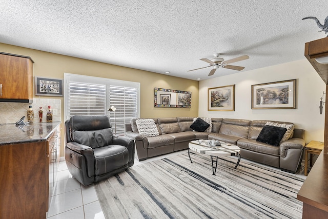 living room with light tile patterned floors, a textured ceiling, and ceiling fan