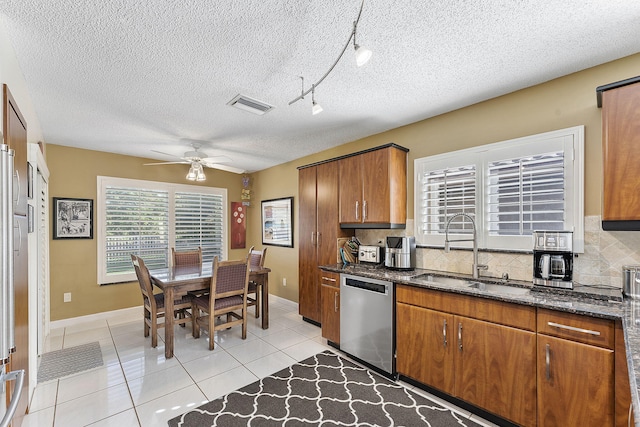 kitchen with sink, stainless steel dishwasher, track lighting, decorative backsplash, and light tile patterned floors