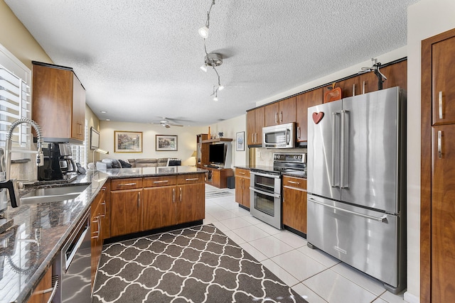 kitchen featuring kitchen peninsula, a textured ceiling, stainless steel appliances, ceiling fan, and light tile patterned floors