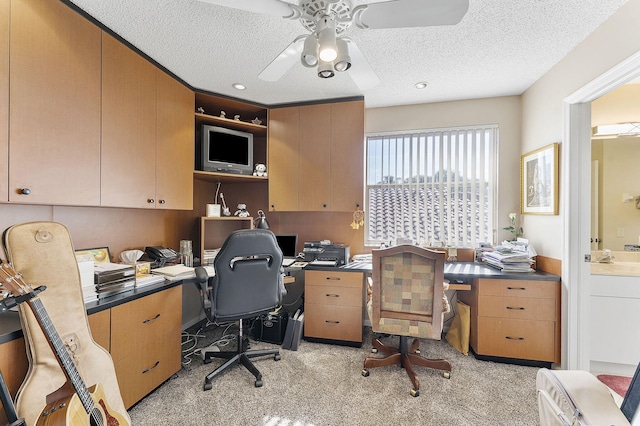 carpeted office space with ceiling fan and a textured ceiling