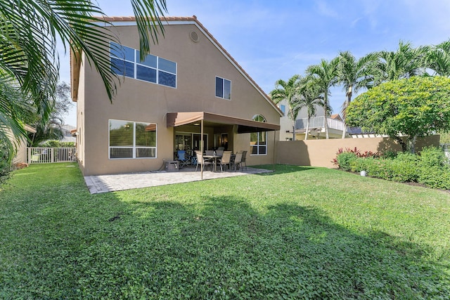 rear view of house with a patio and a lawn