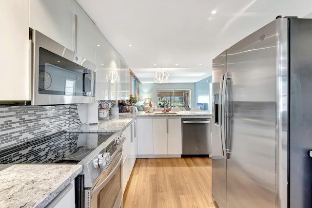 kitchen with appliances with stainless steel finishes, light hardwood / wood-style flooring, white cabinetry, and light stone counters