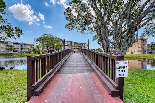 surrounding community with a water view and a yard