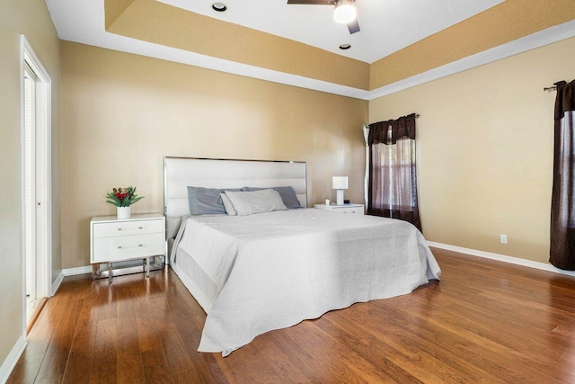 bedroom featuring a tray ceiling, ceiling fan, and dark hardwood / wood-style flooring