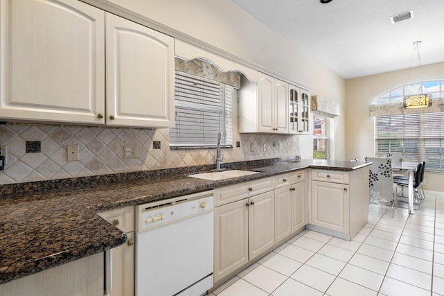 kitchen featuring a textured ceiling, sink, dark stone countertops, dishwasher, and hanging light fixtures