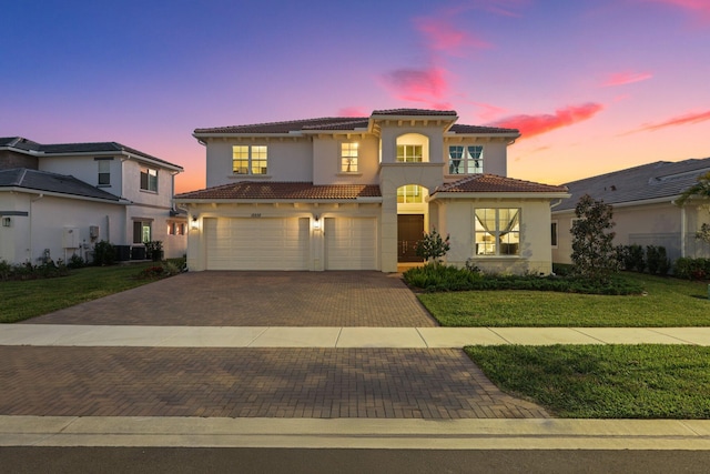 mediterranean / spanish-style home featuring a garage and a lawn