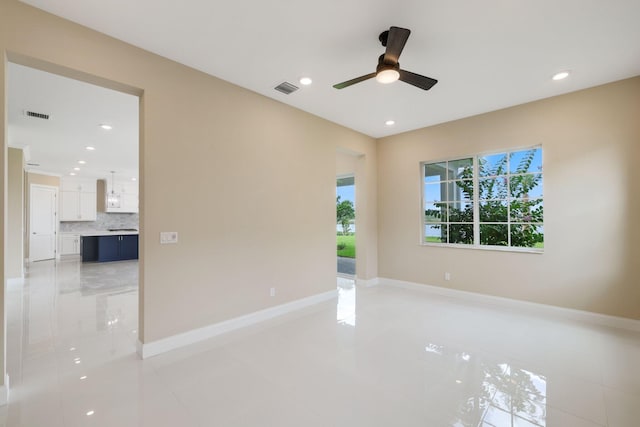 tiled spare room with ceiling fan