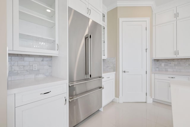 kitchen with white cabinets, decorative backsplash, light tile patterned floors, and built in refrigerator