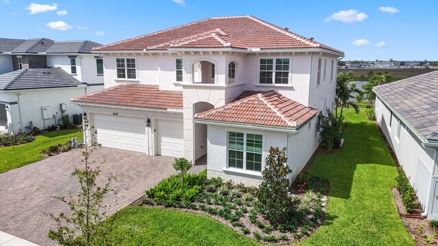 mediterranean / spanish home featuring a garage and a front yard