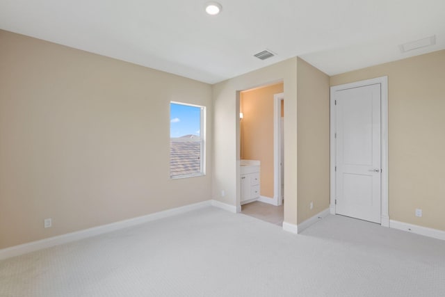 unfurnished bedroom with connected bathroom and light colored carpet