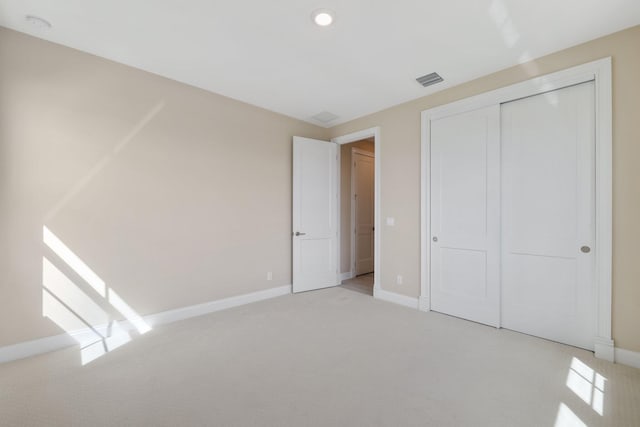 unfurnished bedroom with light colored carpet and a closet