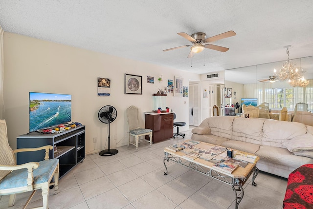 living room featuring a textured ceiling, light tile patterned flooring, and ceiling fan with notable chandelier