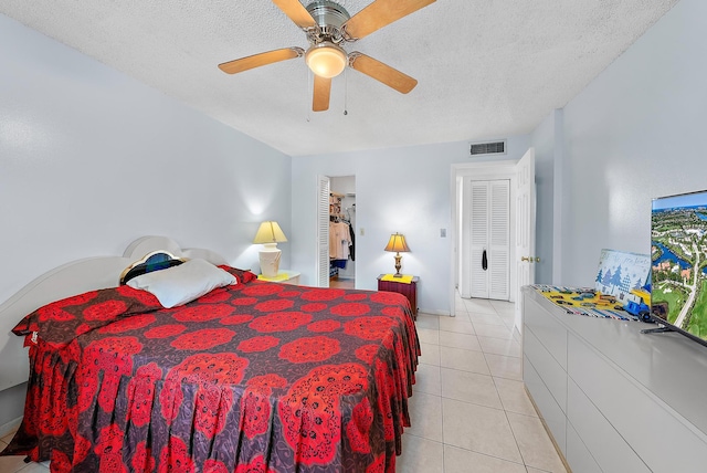 bedroom with ceiling fan, light tile patterned flooring, and a textured ceiling