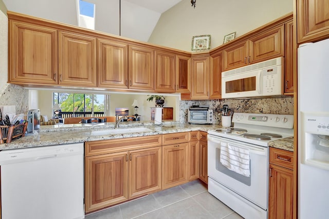 kitchen featuring sink, kitchen peninsula, lofted ceiling, white appliances, and light tile patterned flooring