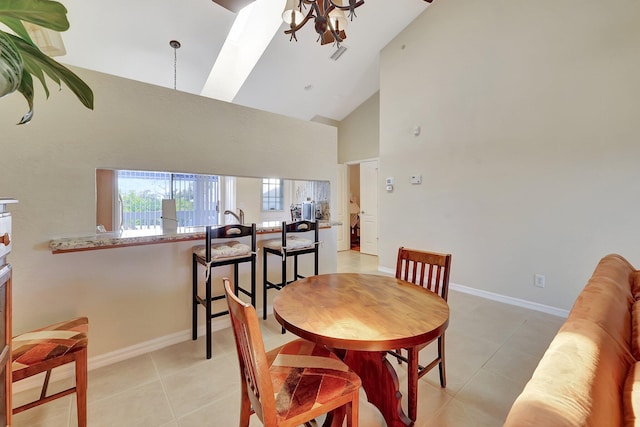 tiled dining room with a skylight, high vaulted ceiling, and a notable chandelier