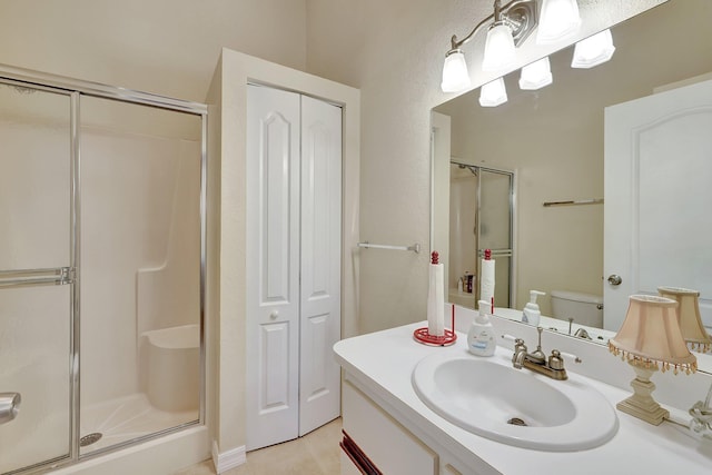 bathroom with tile patterned floors, vanity, toilet, and a shower with shower door