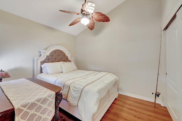 bedroom with ceiling fan, a closet, light hardwood / wood-style floors, and vaulted ceiling