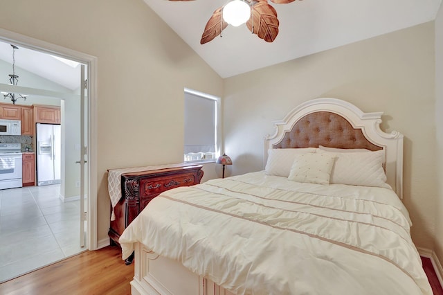 bedroom featuring ceiling fan, white fridge with ice dispenser, lofted ceiling, and hardwood / wood-style flooring