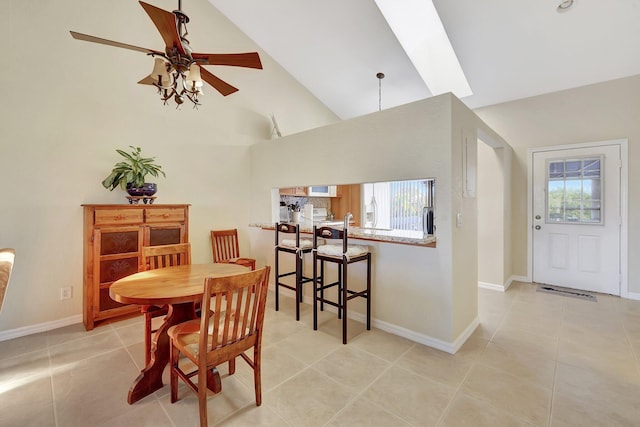 tiled dining room with high vaulted ceiling, ceiling fan, and a wealth of natural light