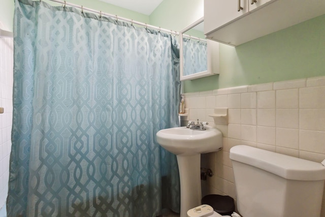 bathroom with toilet, tile walls, and a shower with shower curtain