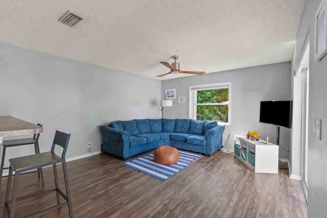 living room featuring ceiling fan, dark wood-type flooring, and a textured ceiling