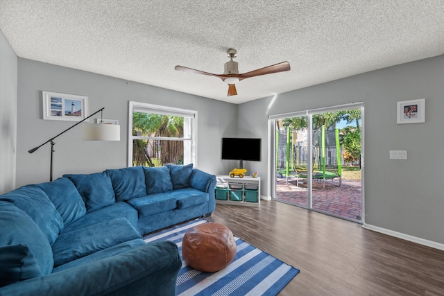 living room featuring wood-type flooring, a textured ceiling, and ceiling fan