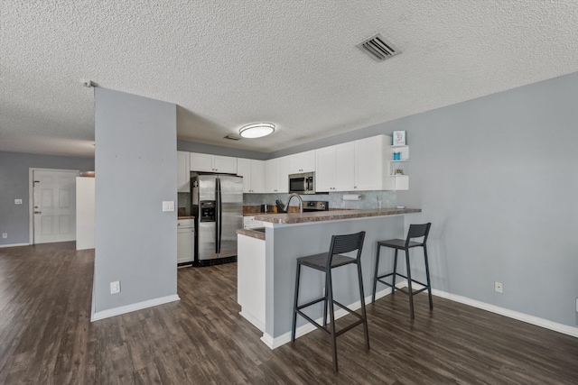 kitchen with white cabinetry, stainless steel appliances, dark hardwood / wood-style flooring, kitchen peninsula, and a breakfast bar area