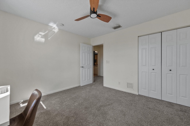 unfurnished bedroom with carpet flooring, ceiling fan, a textured ceiling, and a closet