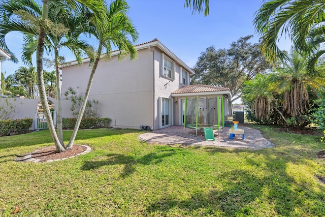 rear view of property featuring a lawn, a sunroom, and a patio