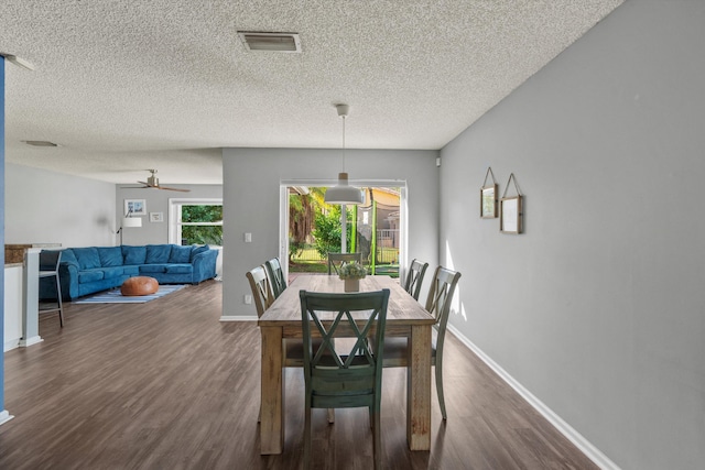 dining area featuring ceiling fan, dark wood-type flooring, and a textured ceiling