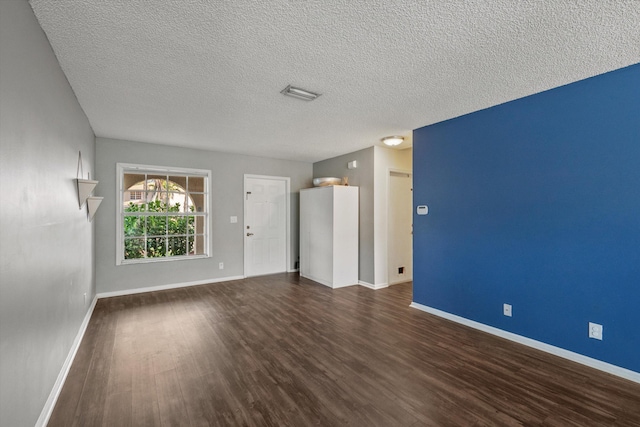 empty room featuring a textured ceiling and dark hardwood / wood-style floors