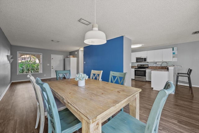 dining space with a textured ceiling, dark wood-type flooring, and sink