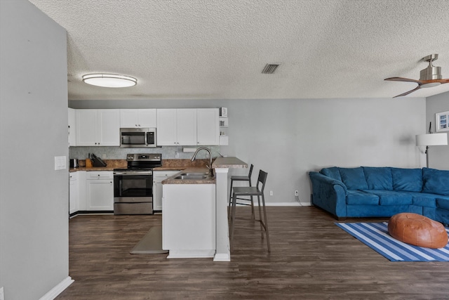 kitchen featuring dark wood-type flooring, sink, white cabinetry, kitchen peninsula, and stainless steel appliances