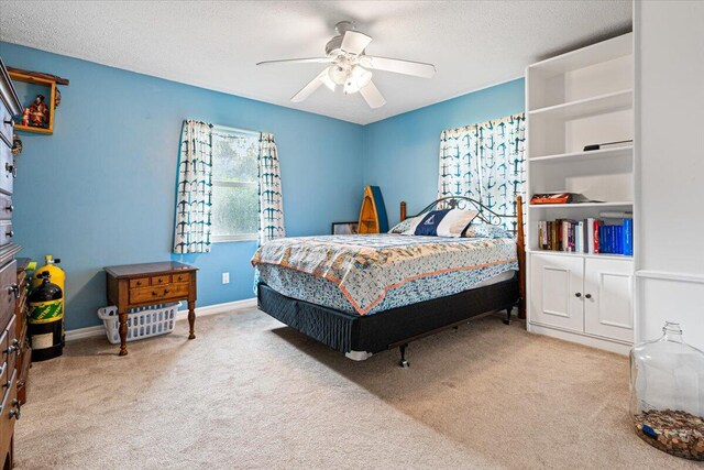 bedroom with light colored carpet, ceiling fan, and a textured ceiling