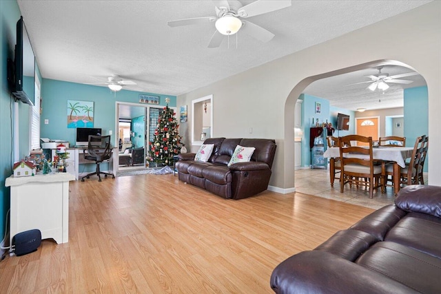 living room featuring a textured ceiling, ceiling fan, and light hardwood / wood-style floors