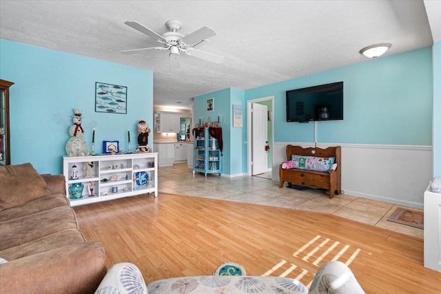 living room featuring ceiling fan, tile patterned flooring, and a textured ceiling