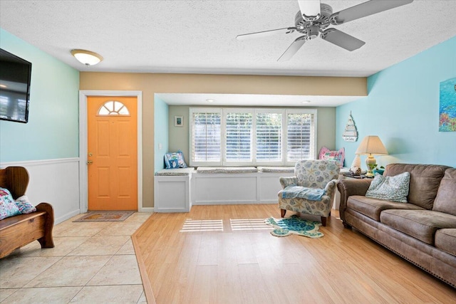 living room with a textured ceiling, ceiling fan, and light tile patterned flooring