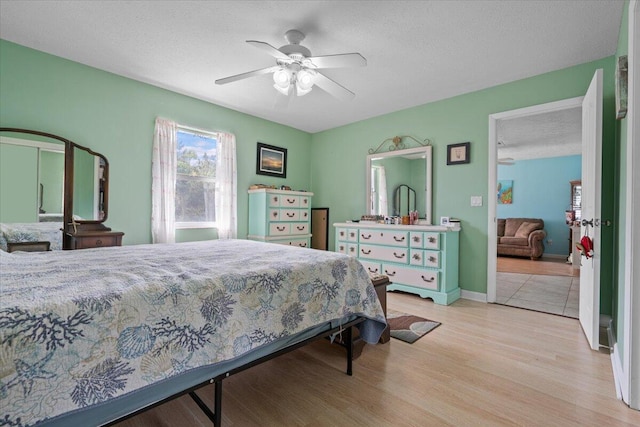 bedroom with a textured ceiling, ceiling fan, and light hardwood / wood-style flooring